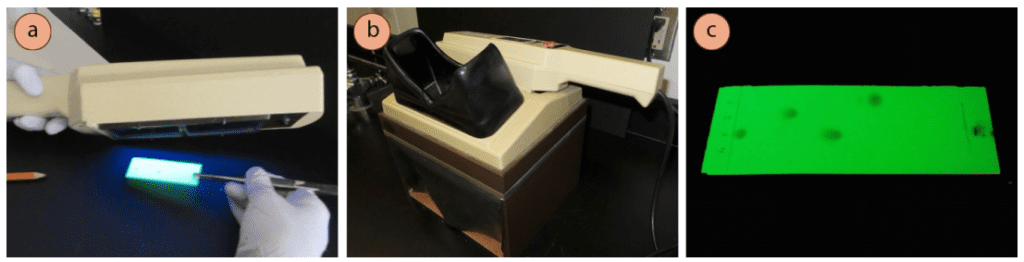 Figura 1: a) Inclinar una l&aacute;mpara UV para visualizar una placa de TLC, b) Caja para proteger los ojos de los da&ntilde;os causados por los rayos UV, c) Apariencia bajo los rayos UV.