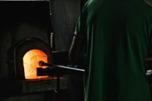 worker blowing glass in workshop